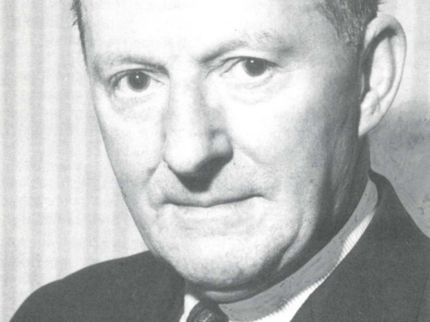 A close up, black and white photograph of theatre manager Roland Hill wearing business attire.